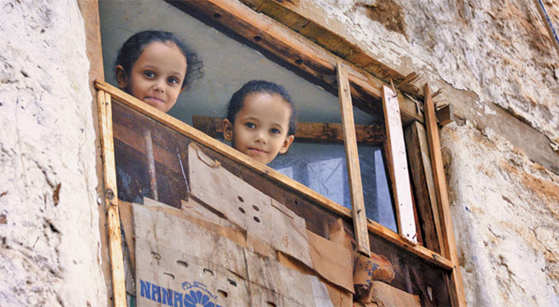  yemen yıkık evin camından bakan küçük 2 kız çocuğu