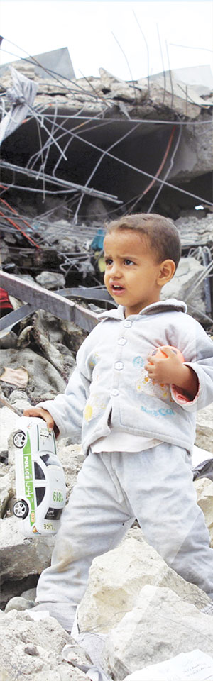 Yemenli çocuk enkaz önünde oyuncak arabasıyla 