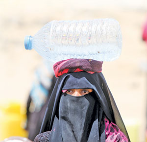 yemenli burkalı başının üstünde su taşıyan kadın  